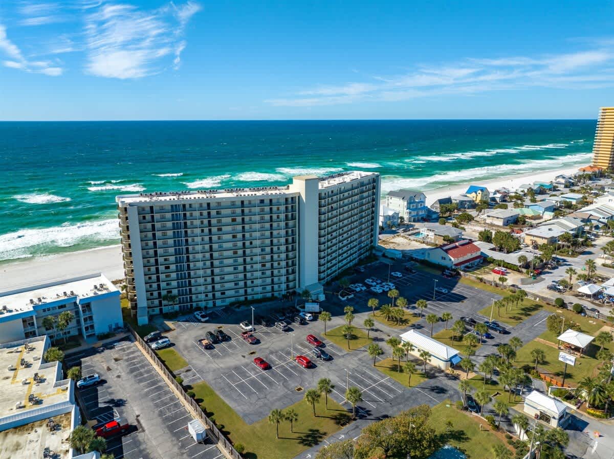 The Summit 816 – Aerial view of a beachfront condo with parking lot and ocean waves in the background.