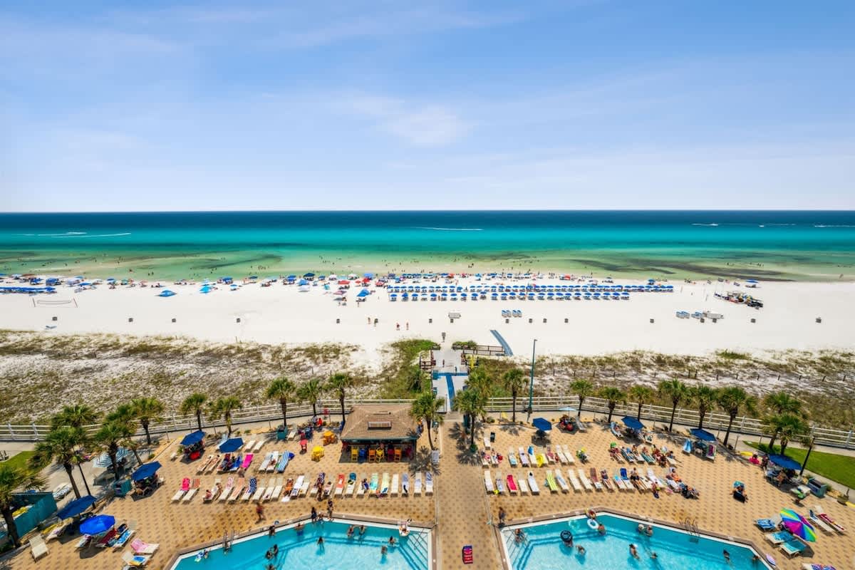 The Summit 1017 – View of a beach, pool area, and umbrellas along the shore.