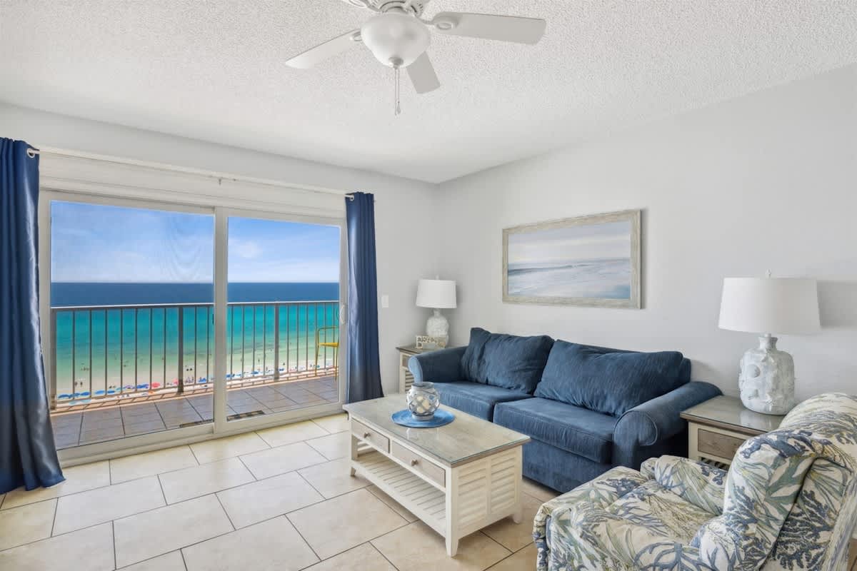 The Summit 1017 – Cozy living room with blue couch, ocean view, and sliding glass doors leading to a balcony.
