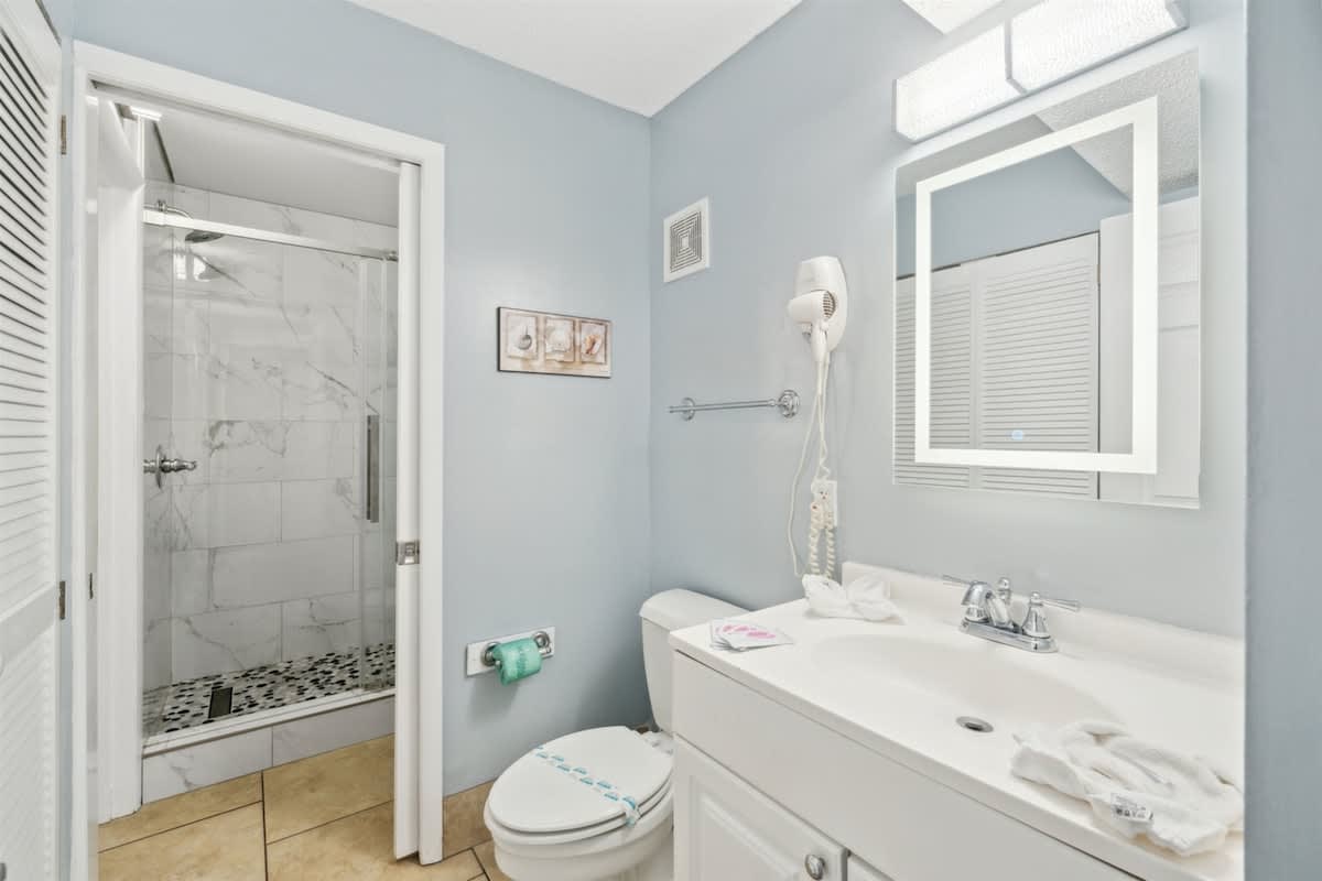 The Summit 1017 – Bathroom with a glass shower, sink, toilet, and light blue walls.