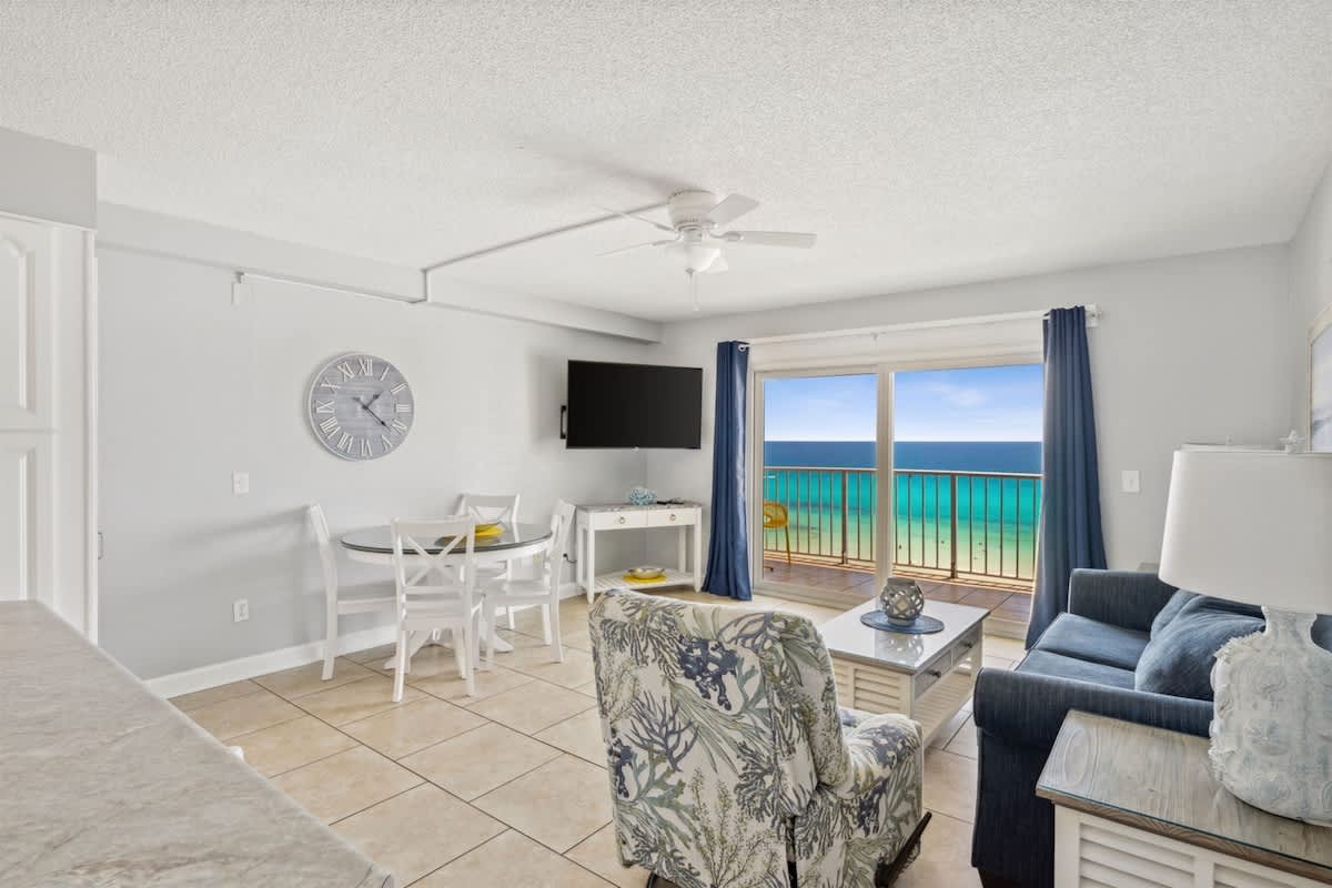 The Summit 1017 – Living room with ocean view, dining area, plush seating, and a TV.
