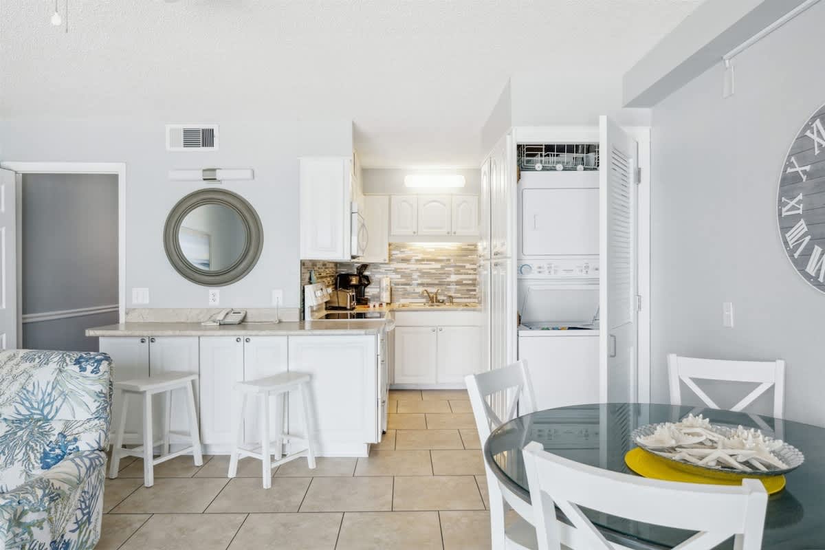 The Summit 1017 – Cozy kitchen and dining area with white cabinetry, tiled flooring, and a round dining table.