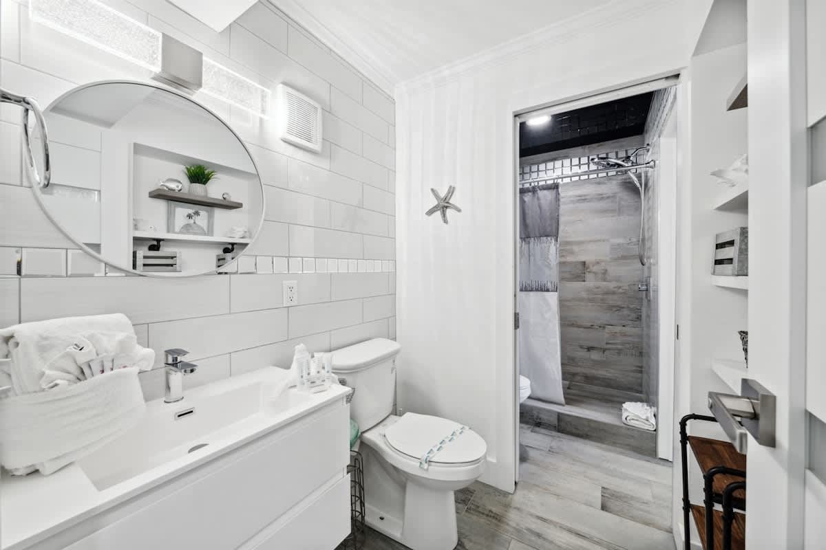 The Summit 702 – Modern bathroom with double sink, large mirror, and a glass-enclosed shower.