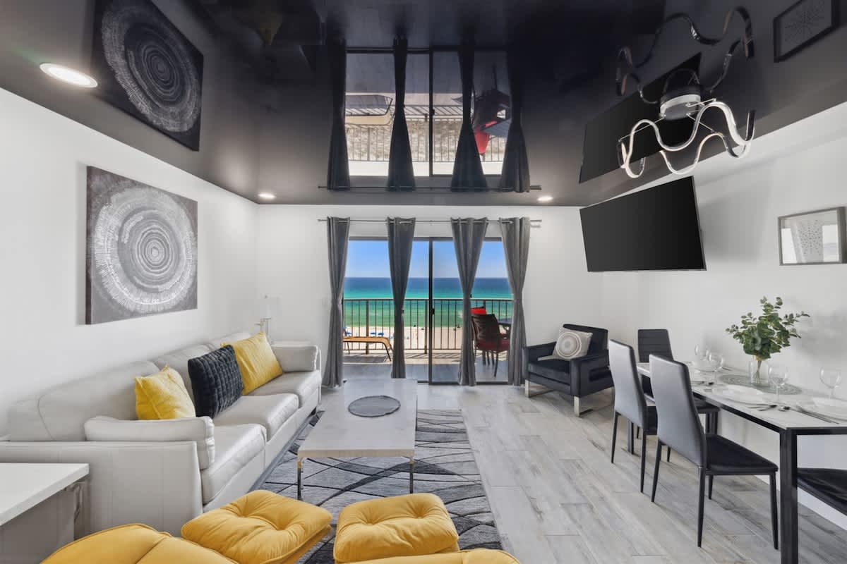 The Summit 702 – Stylish living room with ocean view, modern furniture, dining table, and balcony access.