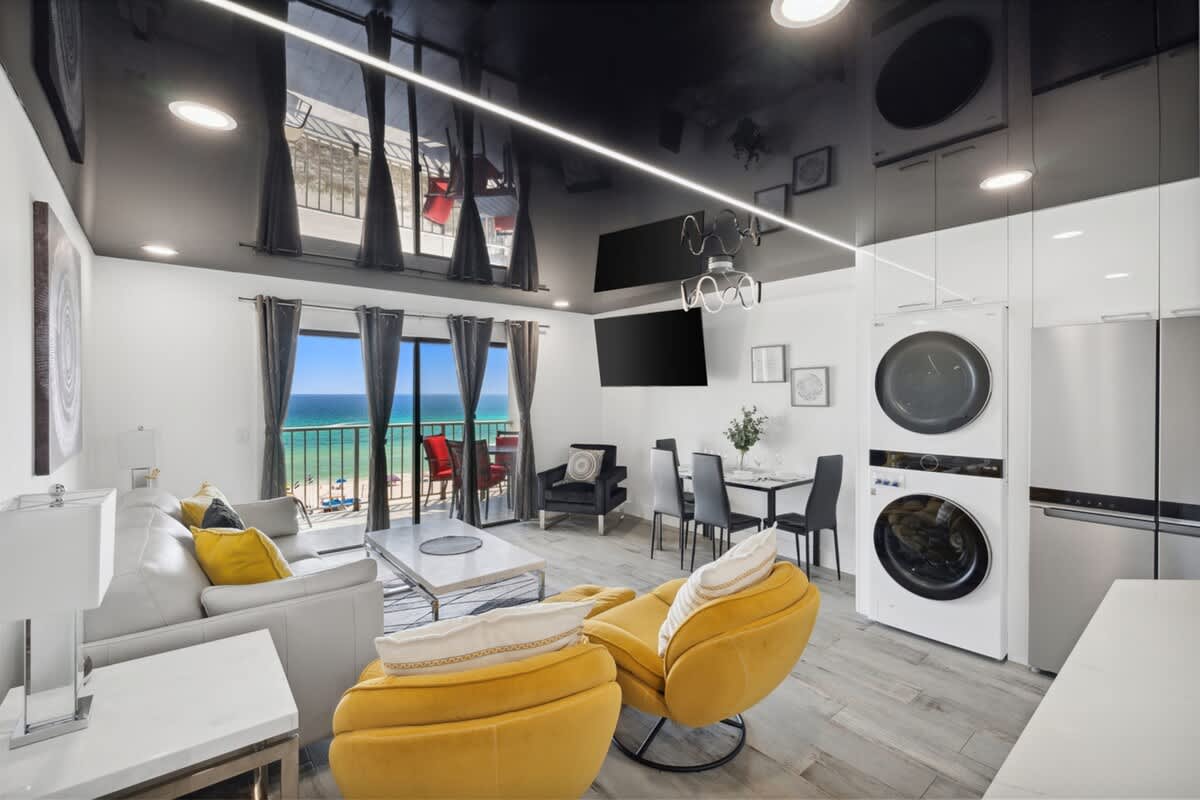 The Summit 702 – Bright living area with yellow chairs, dining table, ocean view, and modern appliances.