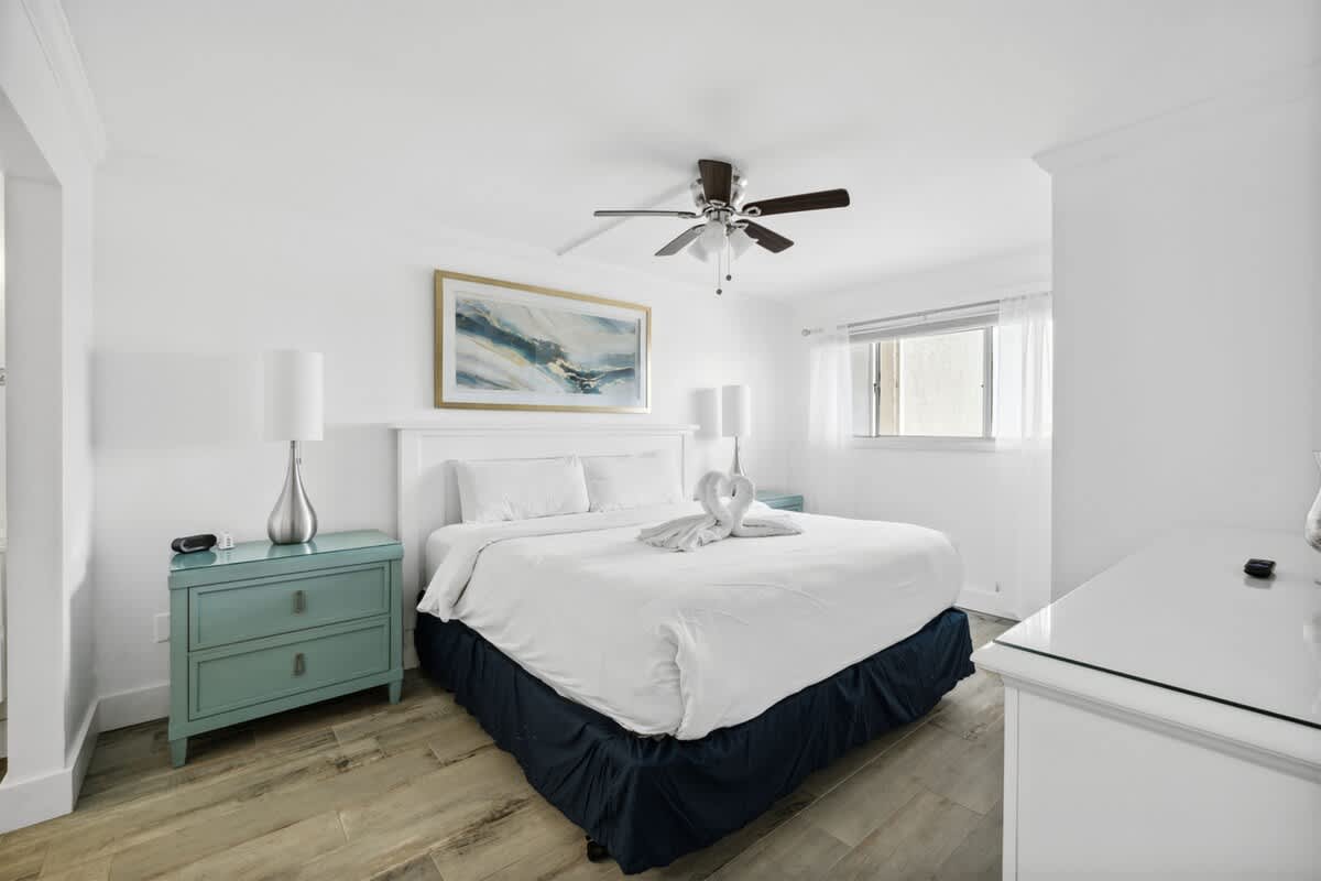 The Summit 702 – Bright bedroom with a king bed, turquoise nightstands, and a window with sheer curtains.