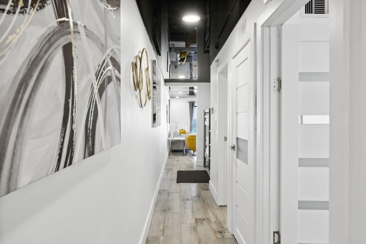 The Summit 702 – Narrow hallway with modern decor, bright lighting, and a view into a living area with yellow chair.