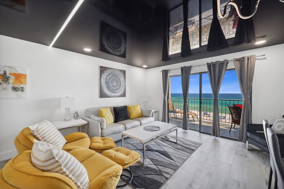 The Summit 702 – Living room with ocean view, gray and yellow decor, seating, and balcony access.