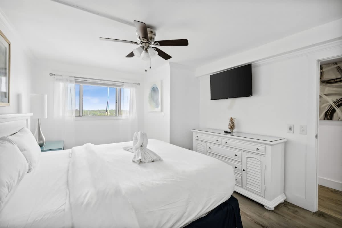 The Summit 702 – Cozy bedroom with a king bed, TV, dresser, and window view of trees.