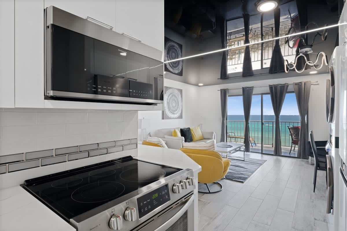 The Summit 702 – Modern living area with kitchen, ocean view, large windows, and colorful furniture.
