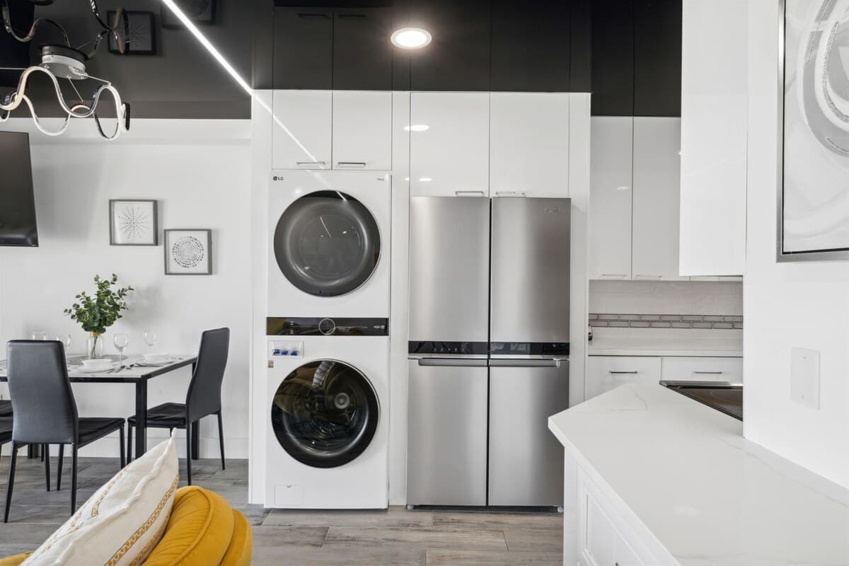 The Summit 702 – Modern kitchen with stainless steel appliances, dining table, and decorative artwork on the walls.
