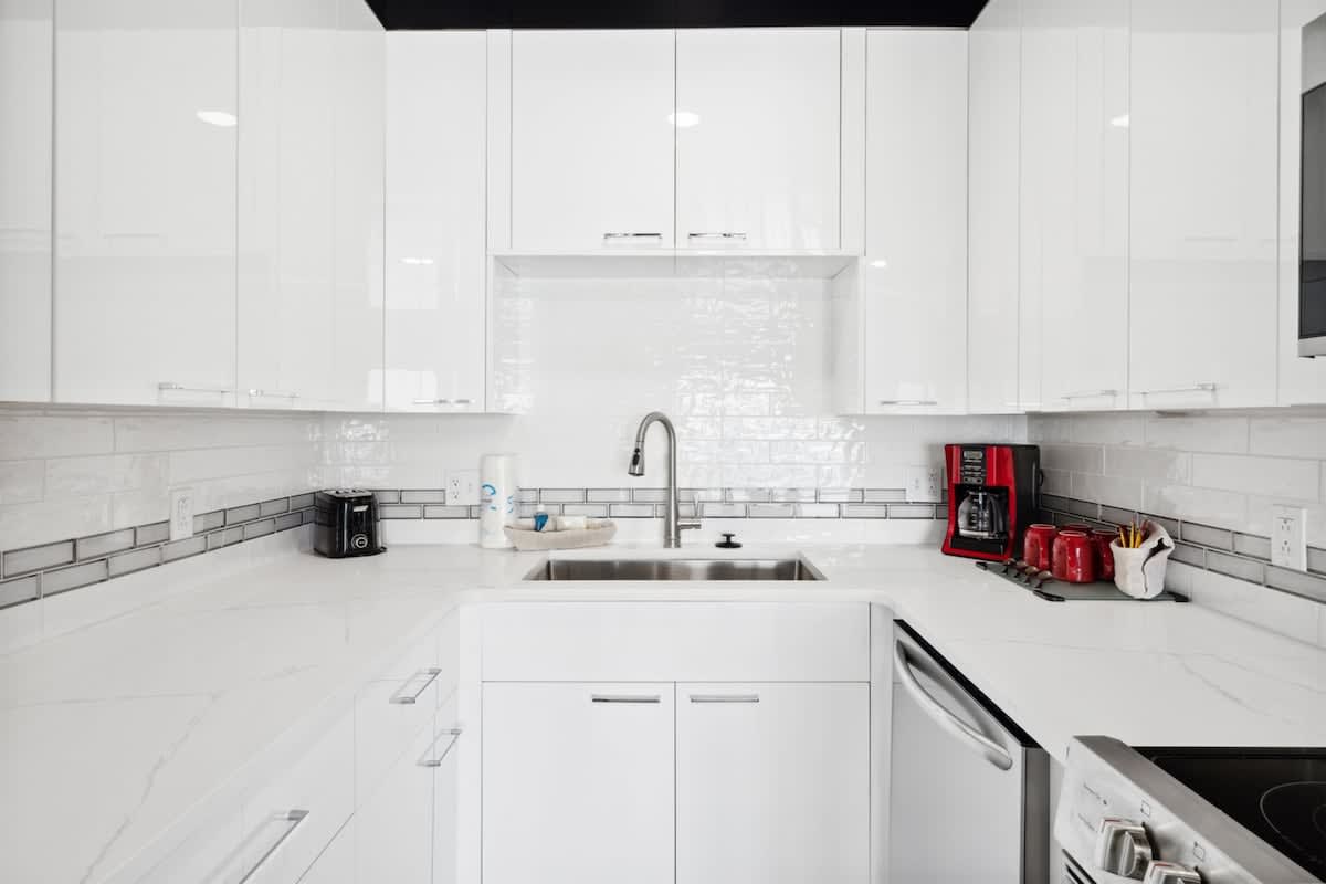 The Summit 702 – Modern kitchen with white cabinets, stainless steel sink, and red coffee maker.