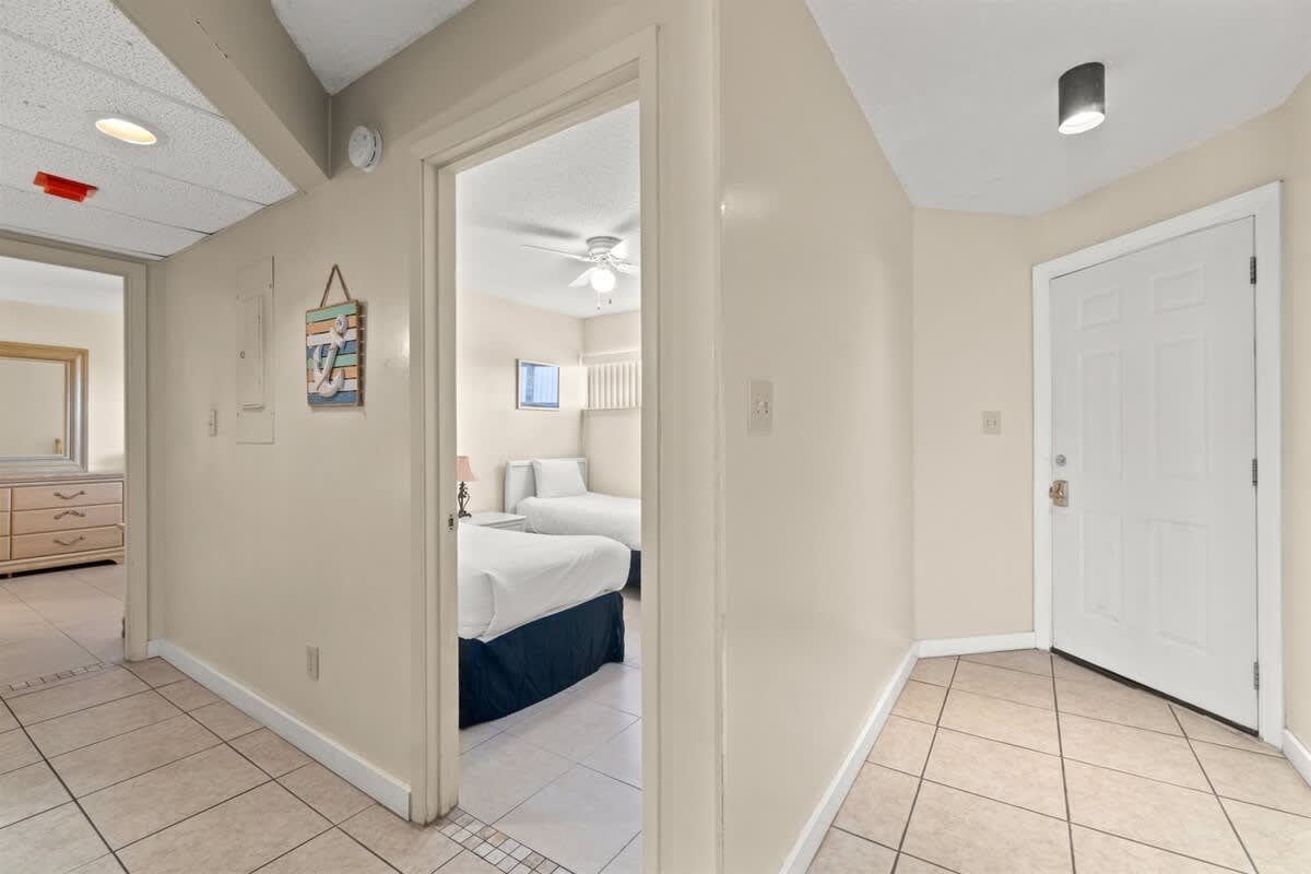Aquavista 405e – Entryway with tile floor, light fixture, and doorway leading to a bedroom with twin beds.