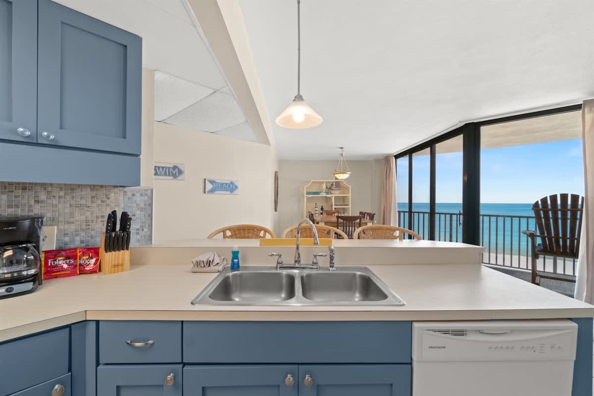 Aquavista 405e – Kitchen with a blue cabinet, sink, and ocean view through large windows.