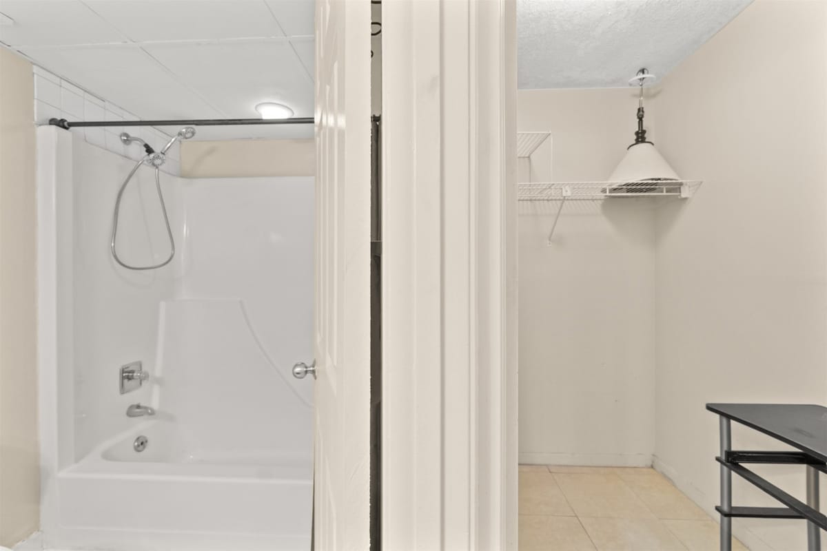 Aquavista 405e – Bathroom with shower and small closet featuring a shelf and a table.