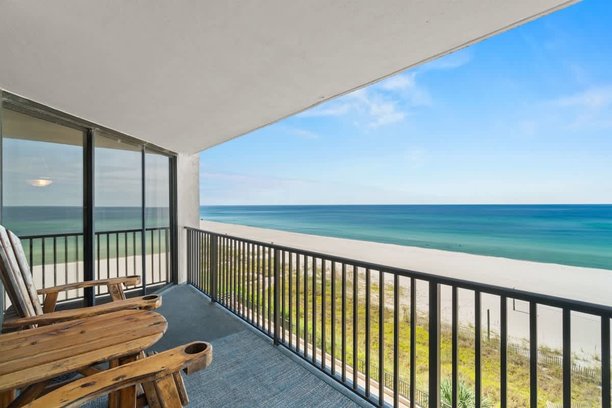 Aquavista 405e – Balcony view of ocean and beach with wooden chairs overlooking the water.