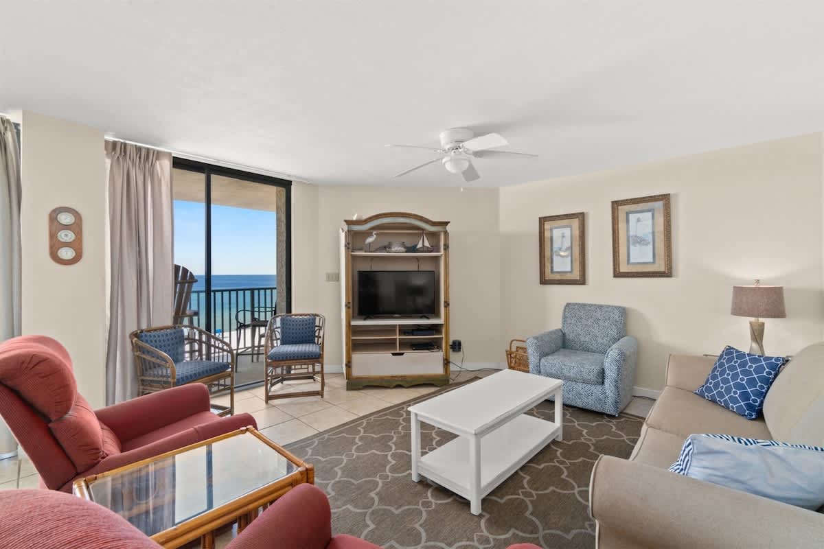 Aquavista 405e – Living room with ocean view, seating area, TV stand, and light-colored furnishings.