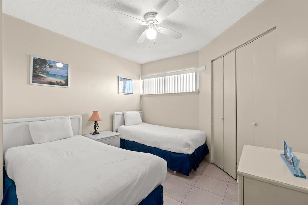 Aquavista 405e – Bedroom with two twin beds, nightstand, dresser, ceiling fan, and closet.