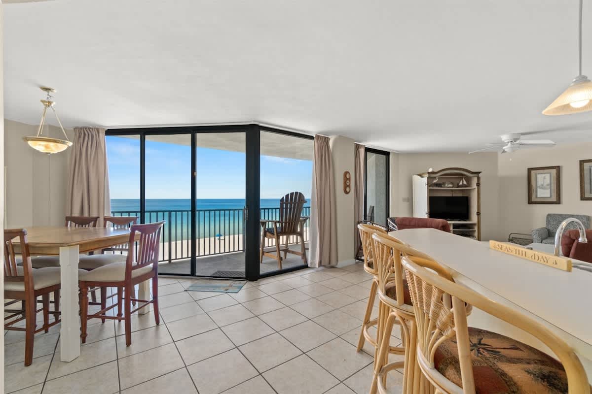 Aquavista 405e – Spacious living area with dining table, kitchen bar, and ocean view from large sliding glass doors.