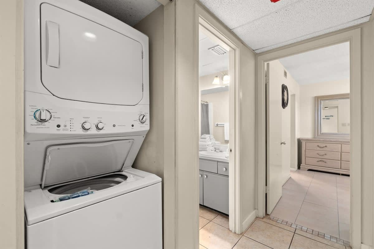 Aquavista 405e – Laundry area with stacked washer and dryer, leading to bathroom and bedroom with dresser.