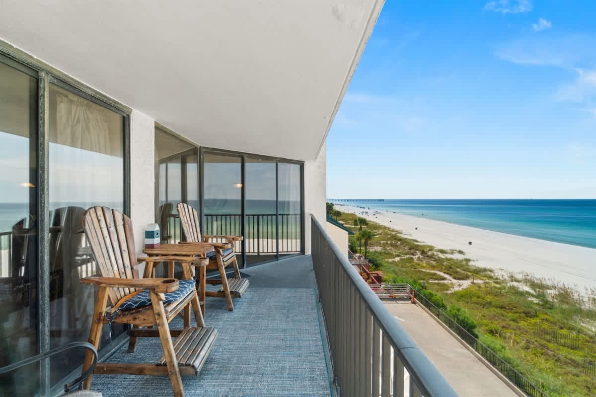 Aquavista 405e – Balcony with two wooden chairs overlooking sandy beach and ocean view.