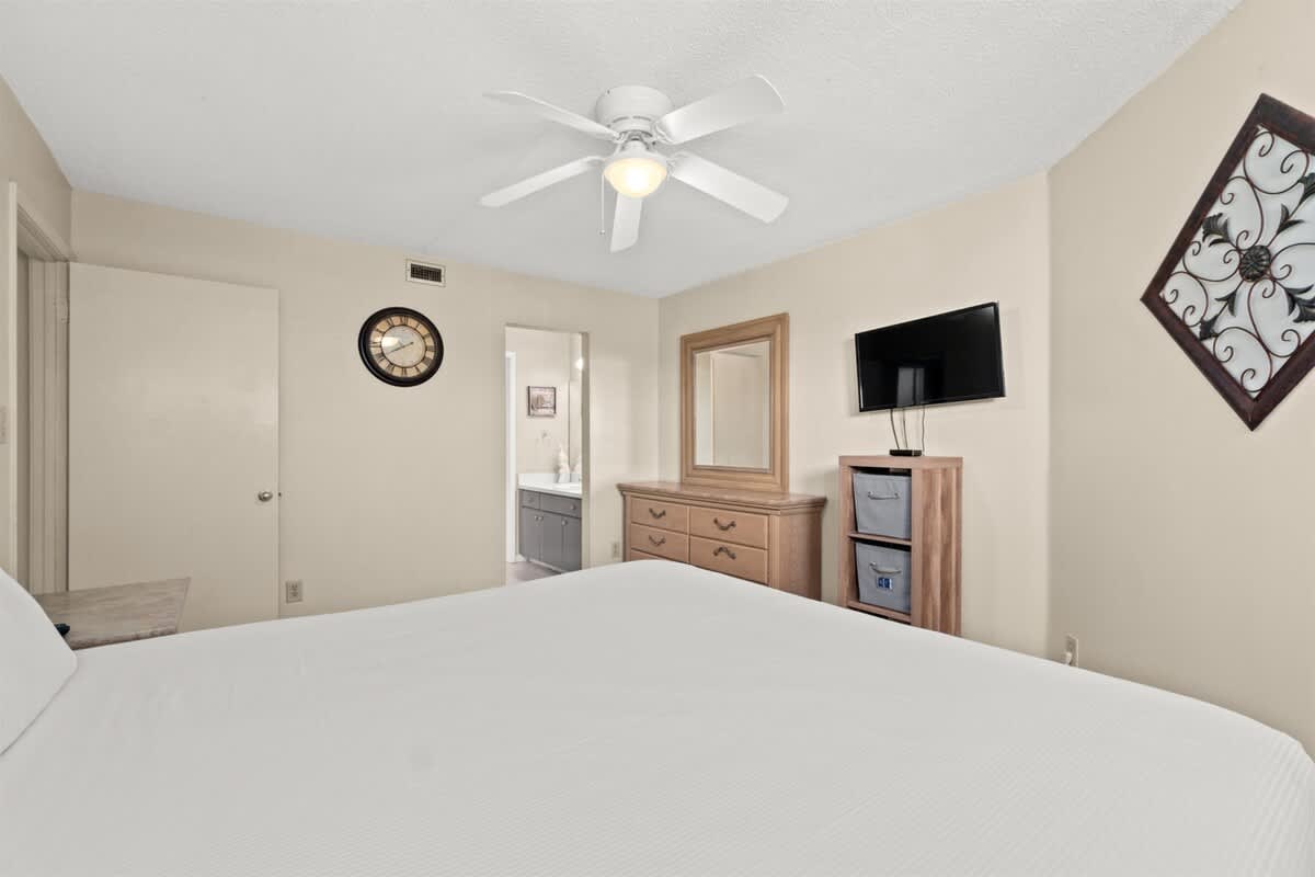 Aquavista 405e – Bedroom with a queen bed, dresser, mirror, TV, and ceiling fan.