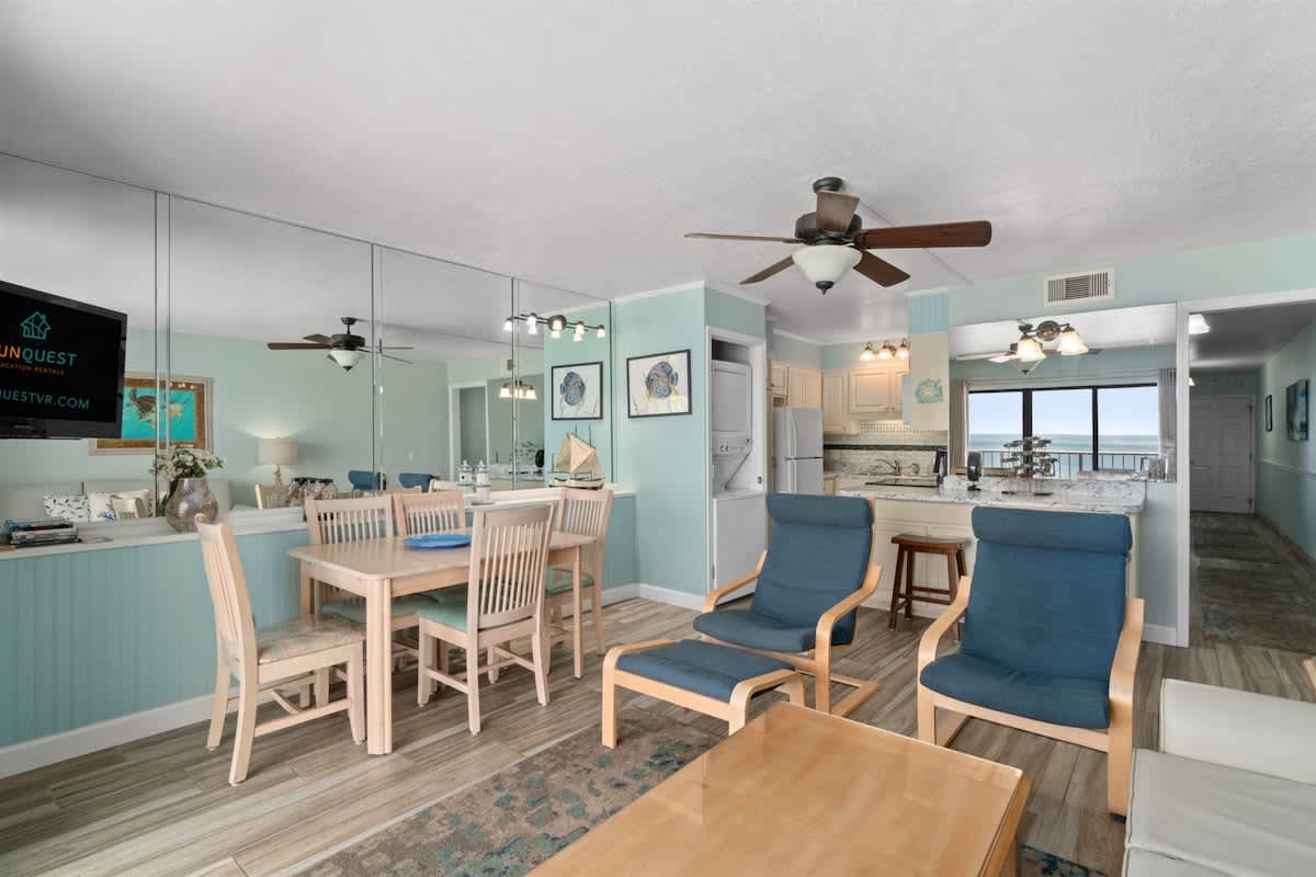 The Summit 1030 – Living area with dining table, kitchen, and ocean view through large window.