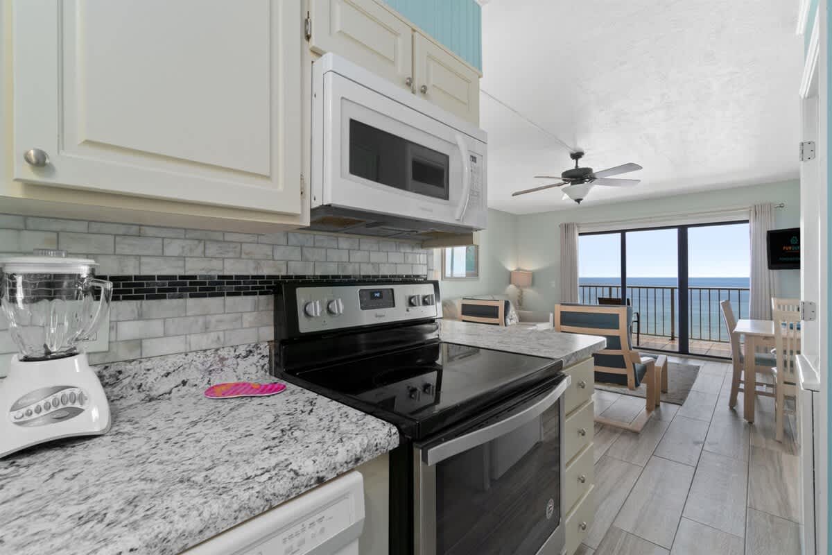The Summit 1030 – Kitchen with granite countertops, seating area, and ocean view through sliding glass doors.