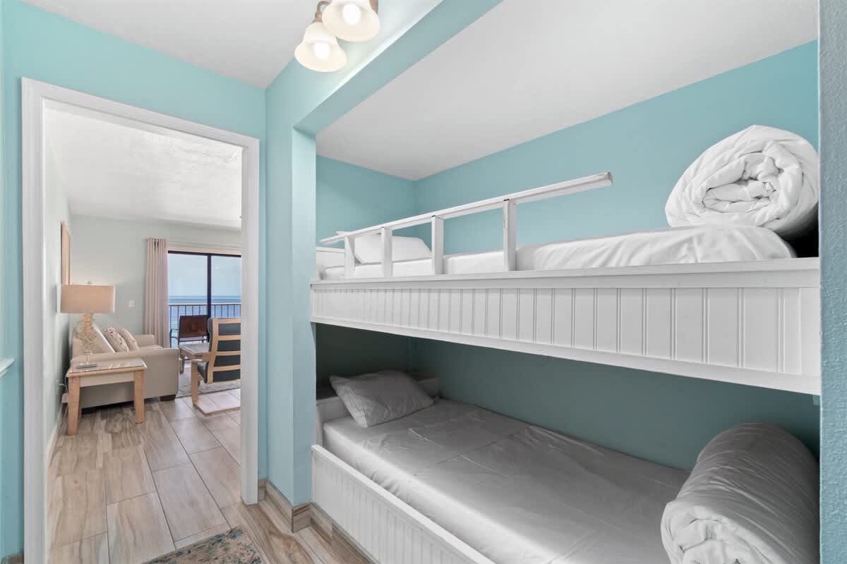The Summit 1030 – Bunk beds in a light blue room with a view of the ocean in the background.