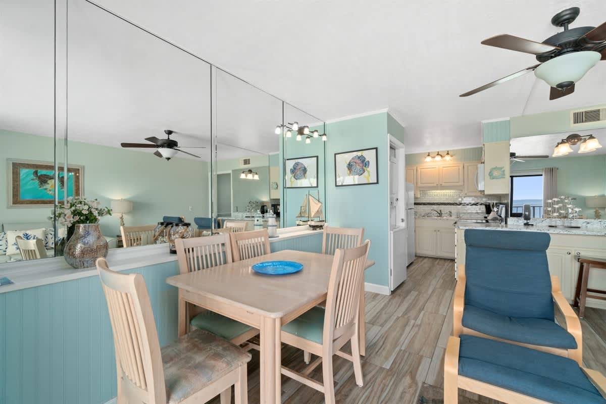 The Summit 1030 – Living and dining area with a table, chairs, kitchen, and ocean view through sliding doors.