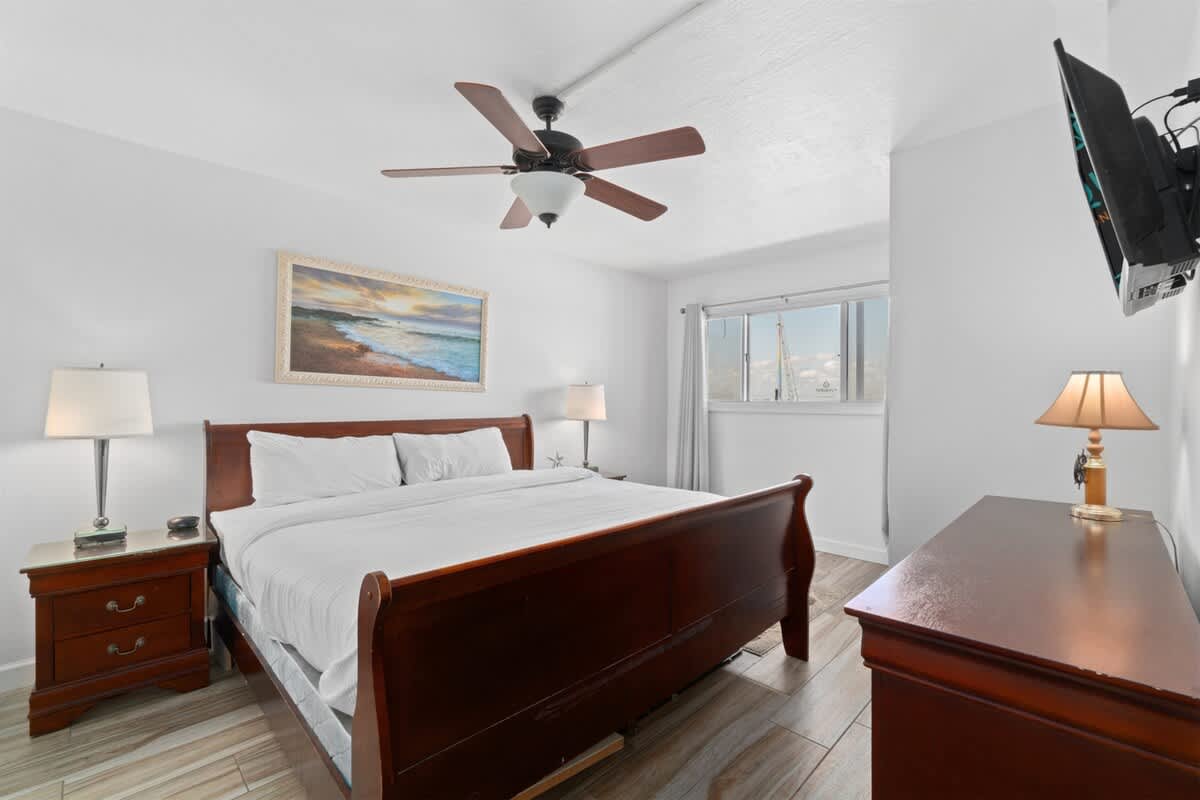 The Summit 1030 – Cozy bedroom with a queen bed, wooden furniture, ceiling fan, and a window showing a view outside.
