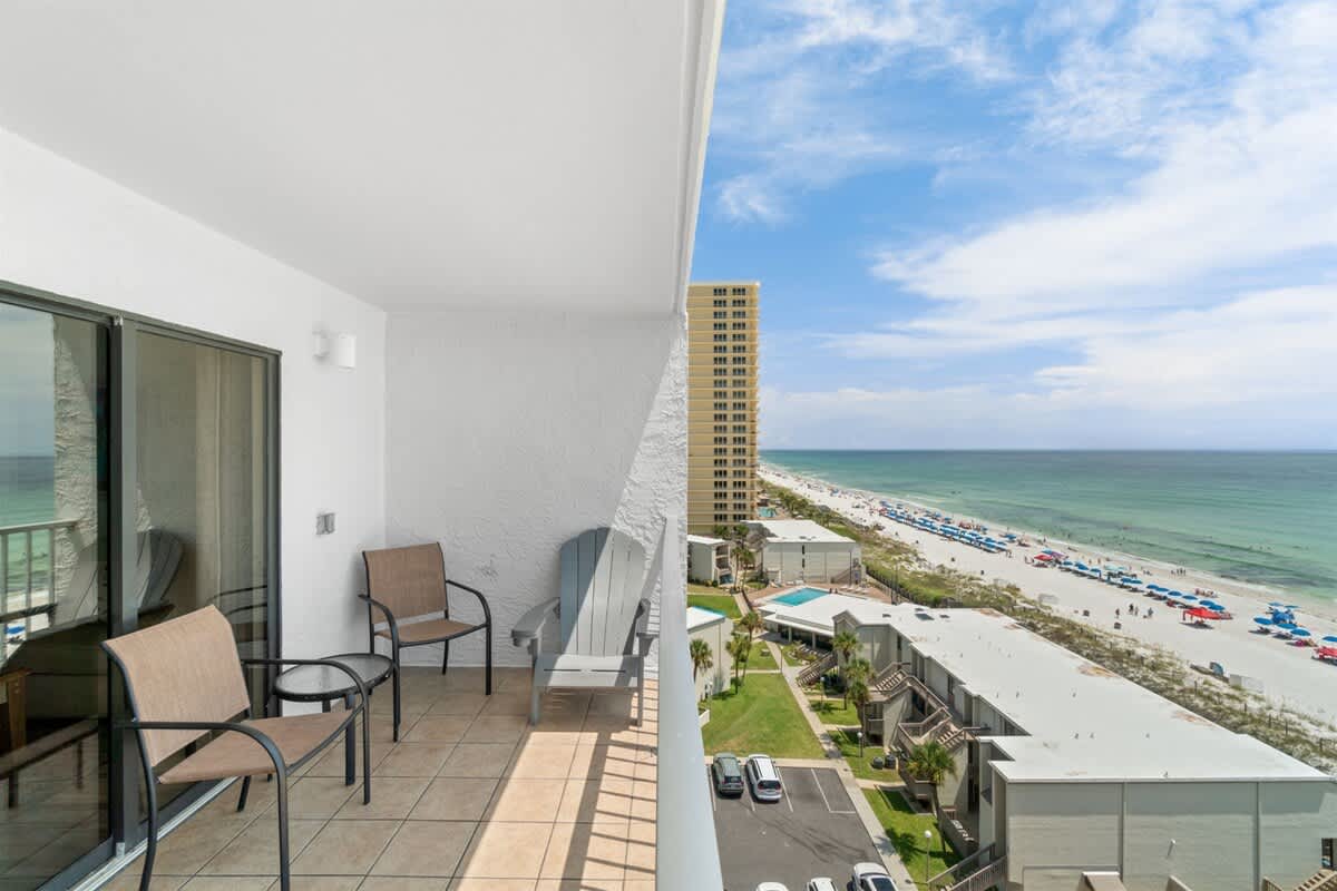 The Summit 1030 – Balcony view with two chairs overlooking beach, ocean, and nearby buildings.