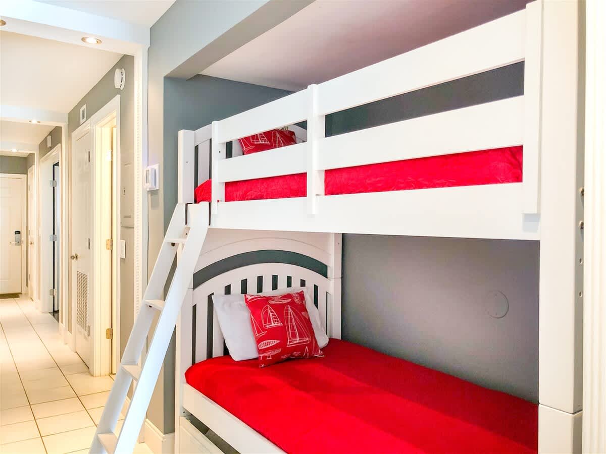 The Summit 611 – Bunk beds with red bedding in a small hallway space with doors leading to other rooms.