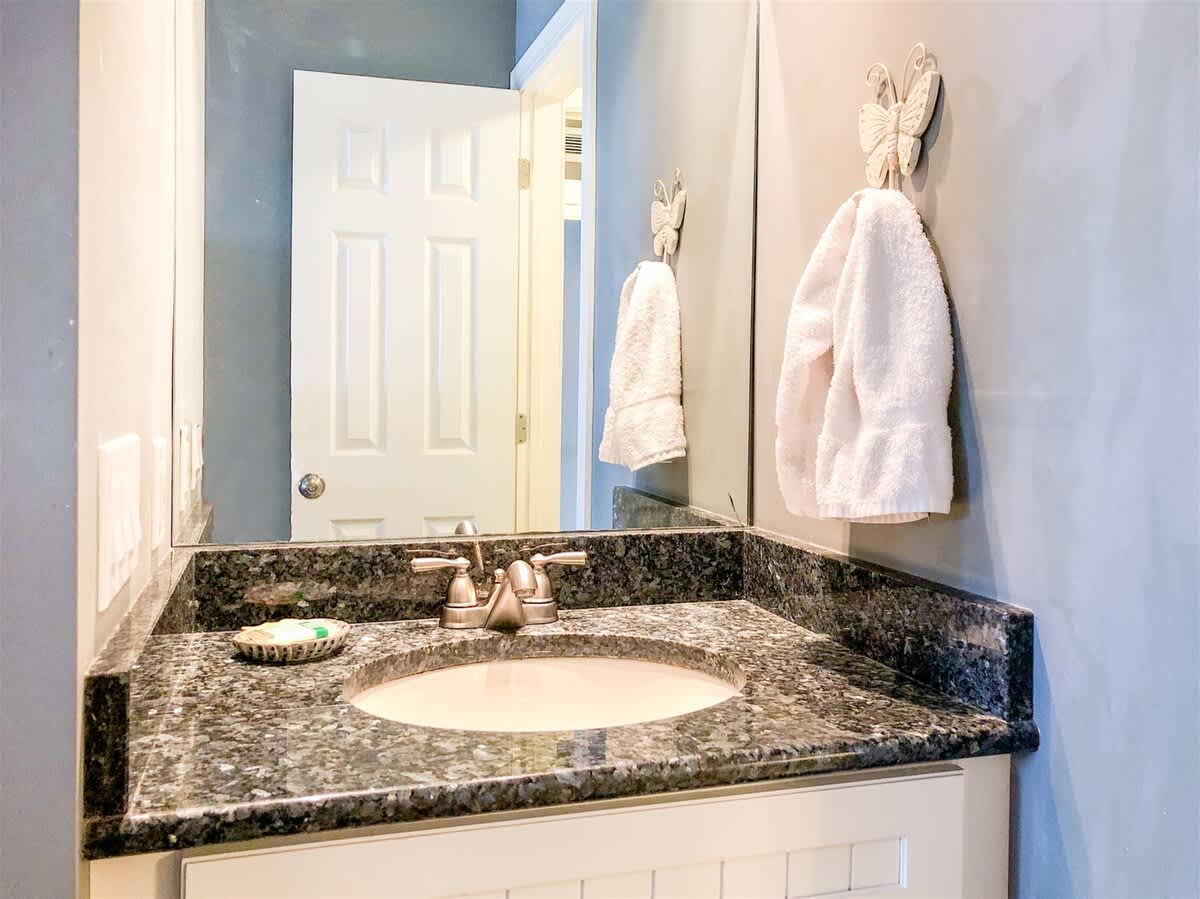 The Summit 611 – Bathroom with granite countertop, round sink, mirror, towels, and a door leading out.
