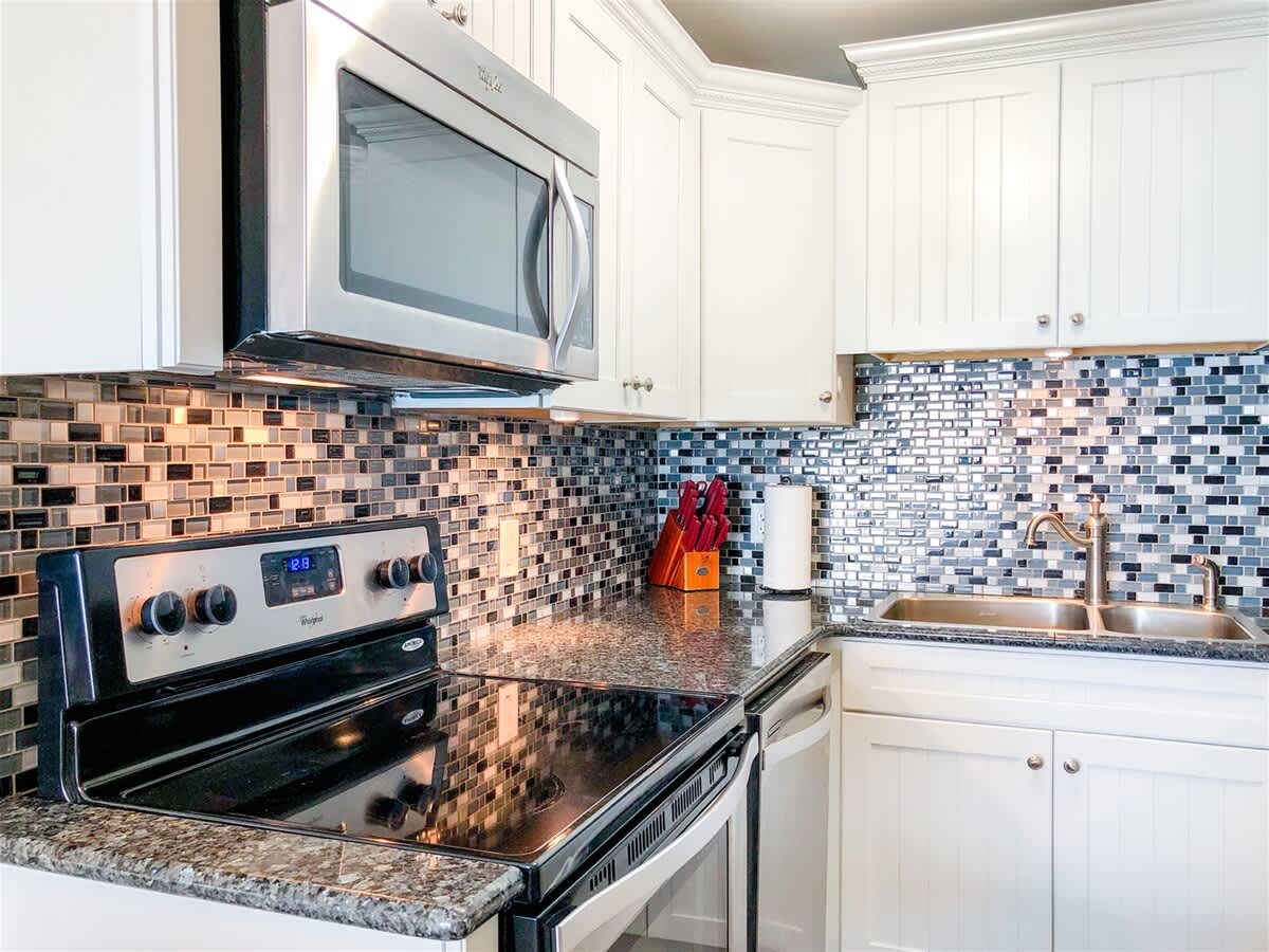 The Summit 611 – Modern kitchen with stainless steel appliances, granite countertops, and mosaic backsplash.