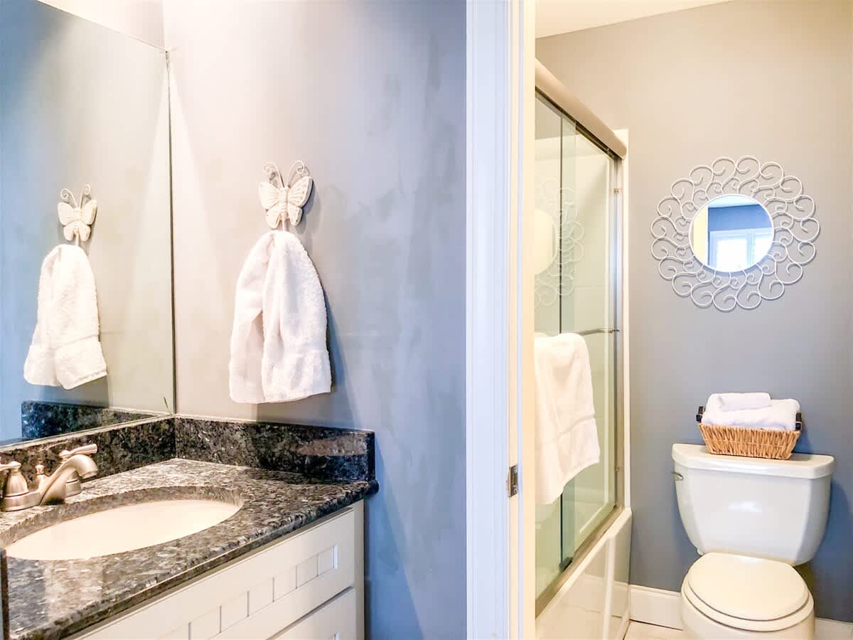 The Summit 611 – Bathroom with gray walls, granite countertop, mirror, shower, toilet, and towels displayed.