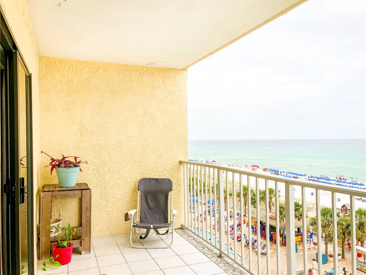 The Summit 611 – Balcony view with a chair, potted plant, and ocean beach below.