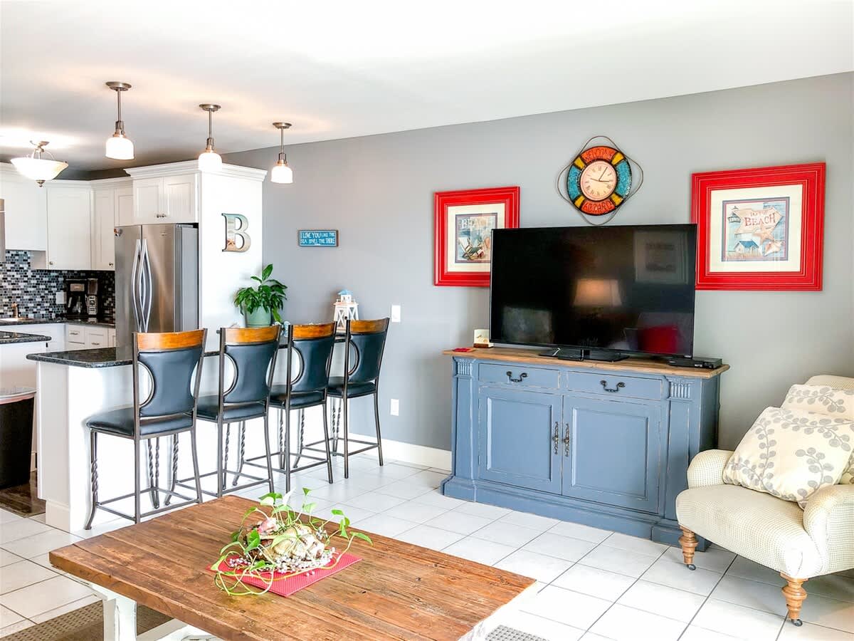 The Summit 611 – Living area with kitchen bar, large TV, decorative wall art, and a wooden coffee table.