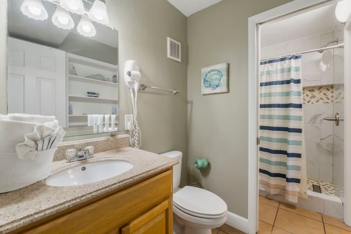 The Summit 1128 – Bathroom with sink, toilet, shower, and shelves containing toiletries.