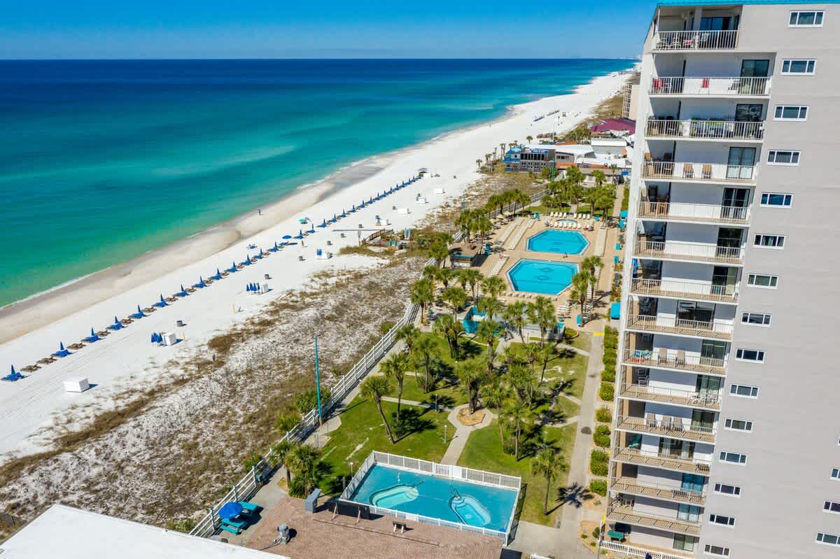 The Summit 1128 – Aerial view of pools, palm trees, sandy beach, and ocean.