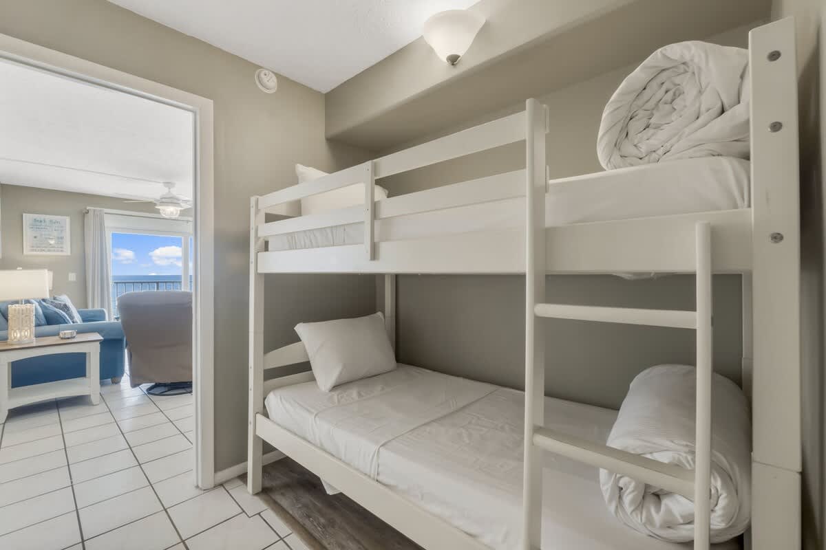 The Summit 1128 – Bunk beds in a small room with a view of the ocean and living area.