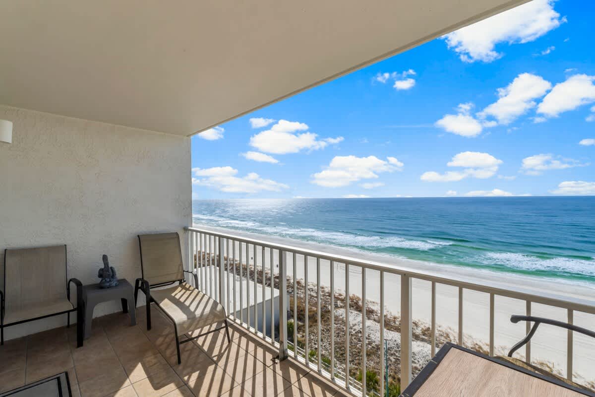 The Summit 1128 – Balcony view with two chairs overlooking the ocean and sandy beach.