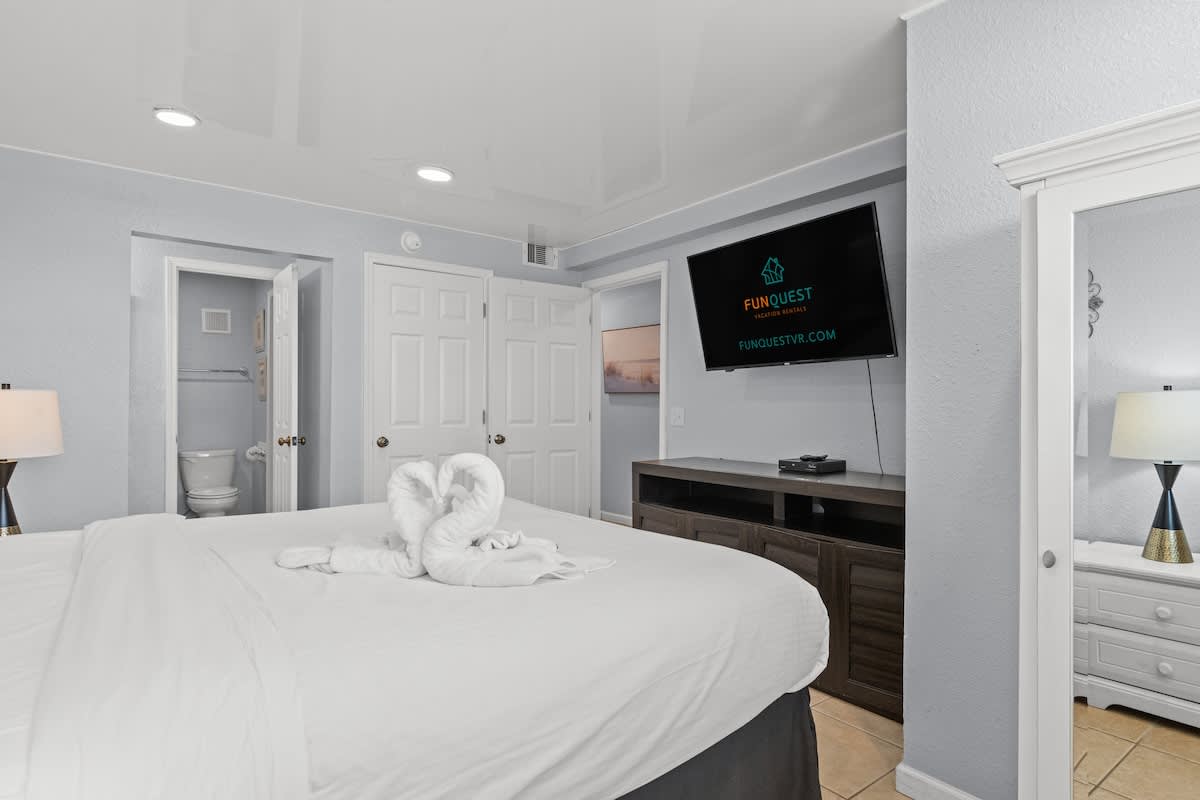 The Summit 1409 – Bedroom with a queen bed, television, and private bathroom access. Decorated with towel swans.