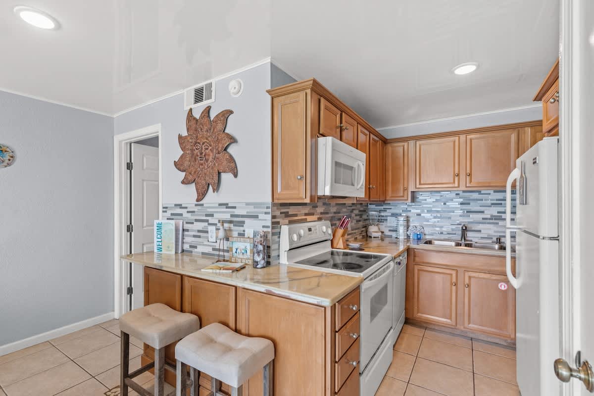 The Summit 1409 – Modern kitchen with wooden cabinets, tiled backsplash, and bar seating.