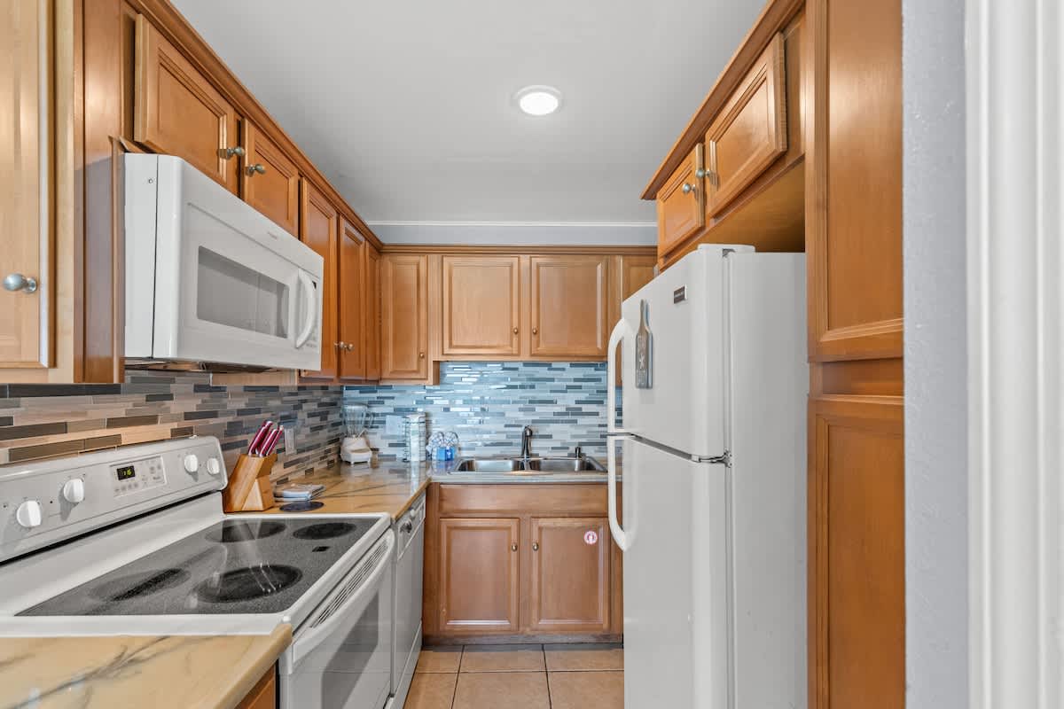 The Summit 1409 – Modern kitchen with wooden cabinets, stainless steel appliances, and blue mosaic tile backsplash.
