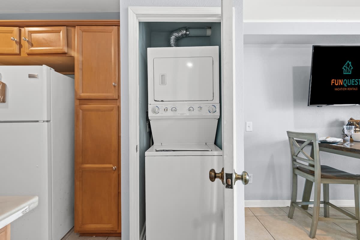 The Summit 1409 – Washer and dryer in a closet next to kitchen, with dining table visible in the background.