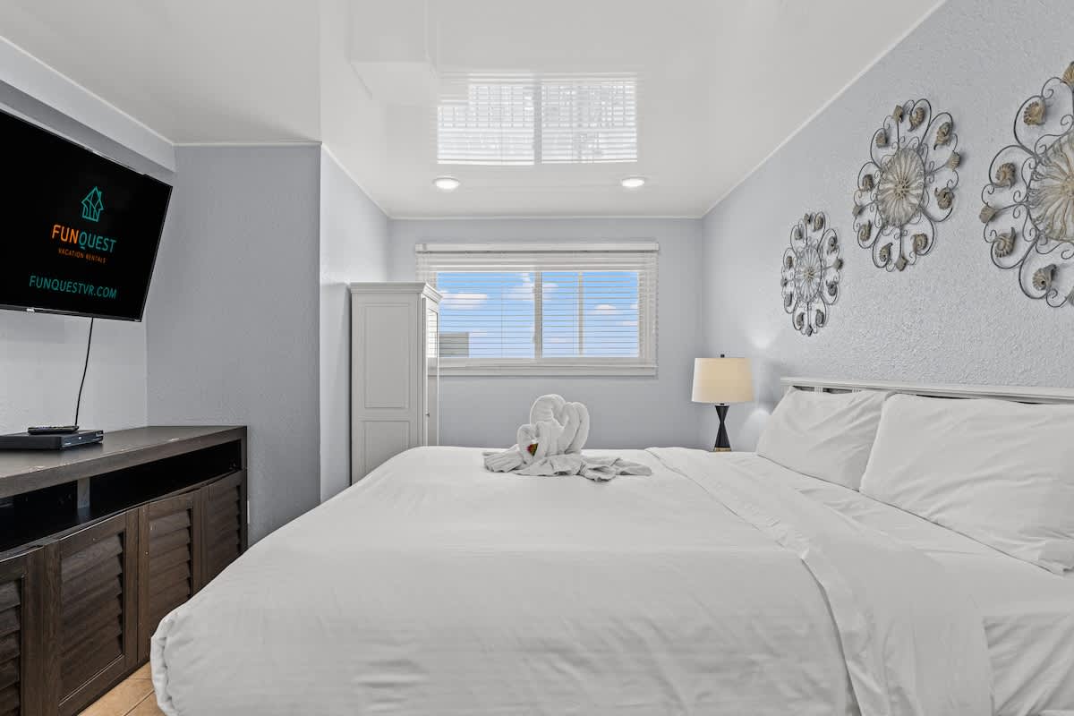 The Summit 1409 – Cozy bedroom with a queen bed, TV, window, and decorative wall art.