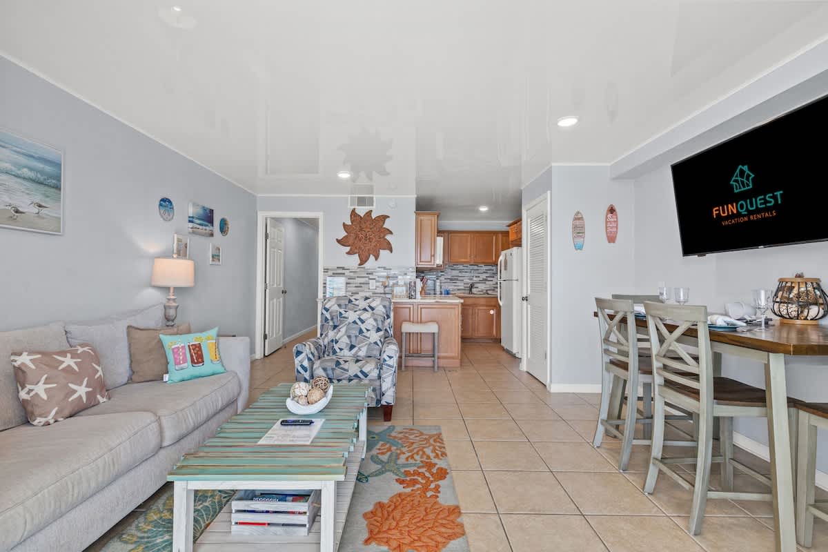The Summit 1409 – Living room with sofa, dining area, kitchenette, decorative art, and natural light from windows