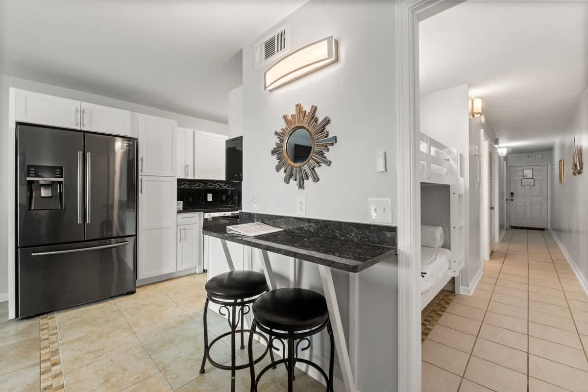 The Summit 620 – Kitchen area with black appliances, bar seating, and a hallway leading to a bunk bed nook.