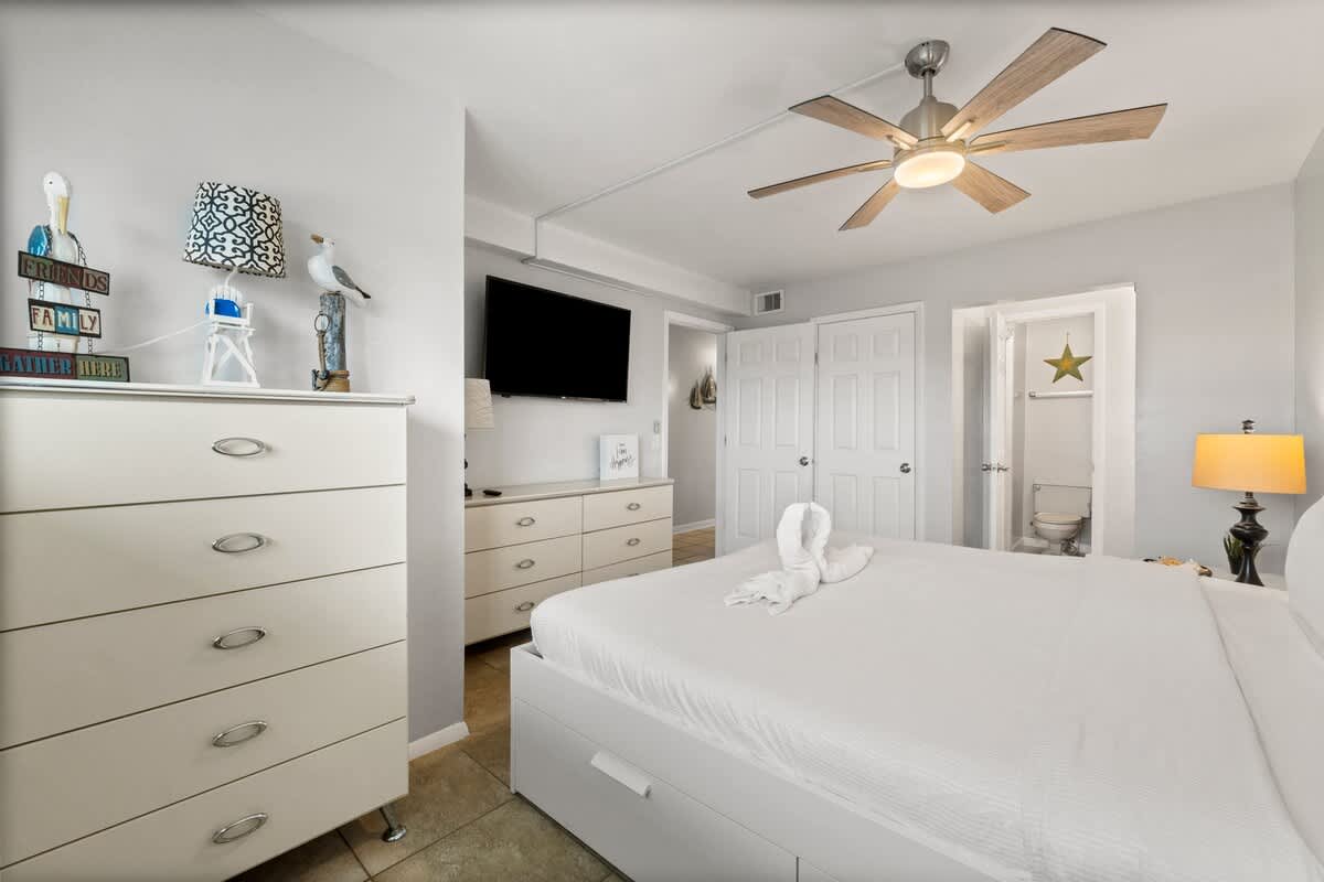 The Summit 620 – Bright bedroom with a king bed, TV, dresser, lamp, and adjoining bathroom.
